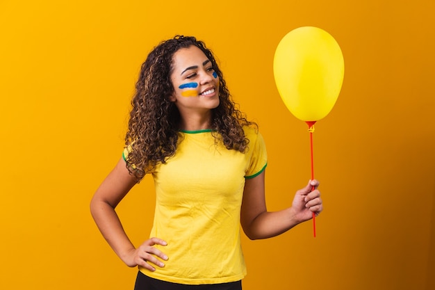 Foto torcedor brasileiro segurando balão amarelo com espaço livre para texto. promoção de jogos do brasil
