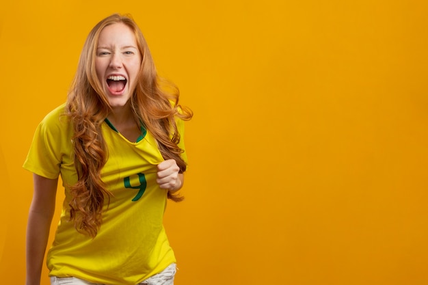 Torcedor do Brasil. Fã de mulher ruiva brasileira comemorando no futebol, jogo de futebol, cores do Brasil.