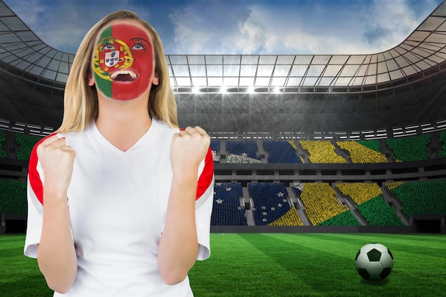 Torcedor portugal entusiasmado com pintura facial torcendo contra um grande estádio de futebol com torcedores brasileiros