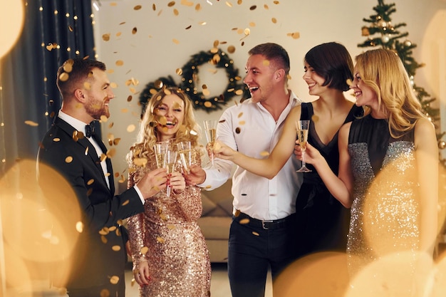 Foto torcendo com champanhe grupo de pessoas tem uma festa de ano novo dentro de casa juntos