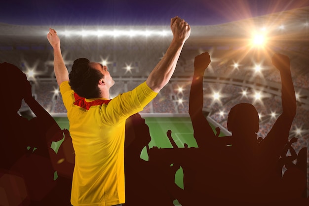Torcer o fã de futebol em camisa amarela contra grande estádio de futebol com luzes