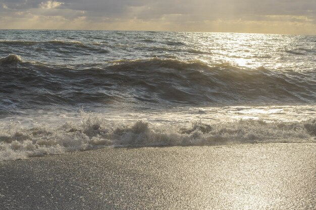 Foto tormenta en el mar en los rayos del atardecer grandes olas, spray.