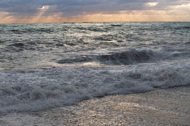Foto tormenta en el mar en los rayos del atardecer grandes olas, spray.