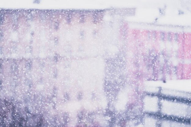 Tormenta de nieve, copos de nieve borrosos, ciudad cubierta de nieve y árboles a la vista desde el décimo piso. Tonificado con humor navideño.