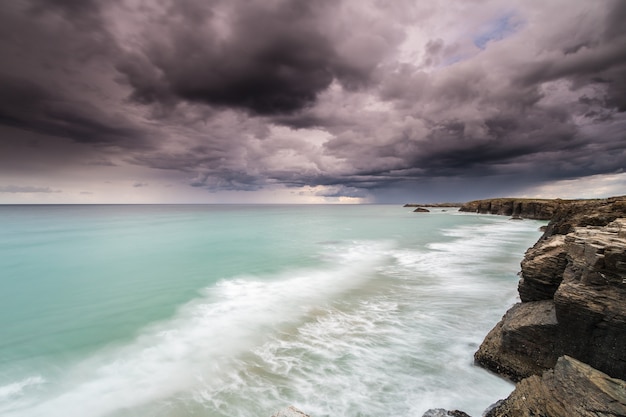 tormenta en la playa de las catedrales con lluvia en el horizonte