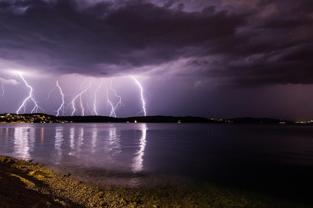 Tormentas eléctricas en el cielo nublado sobre el lago por la noche