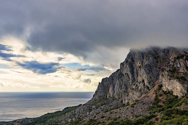 Tormentosas nubes grises sobre las montañas y el mar en la costa