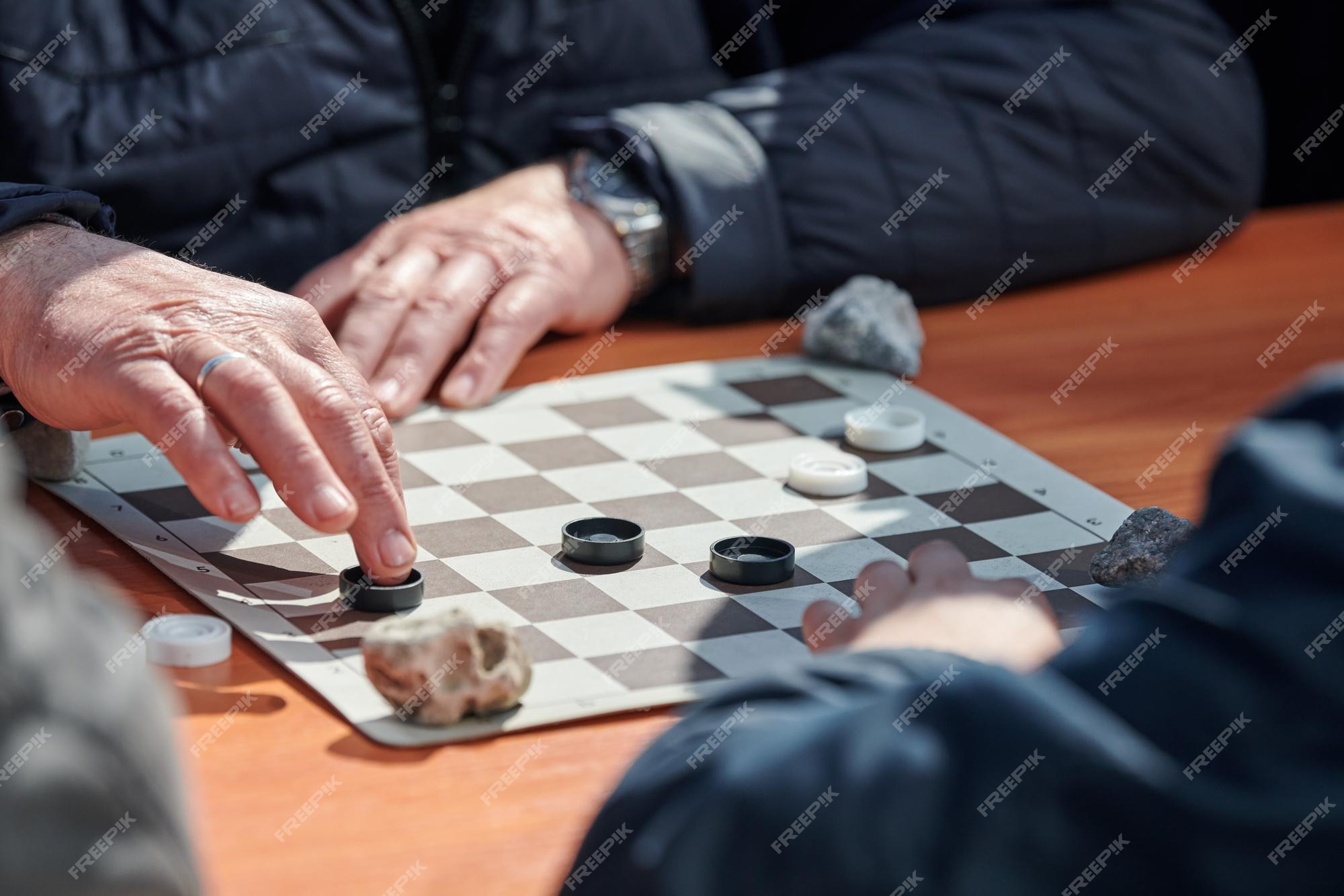 Torneio de damas ao ar livre no tabuleiro de damas de papel na mesa fechar  as mãos dos jogadores