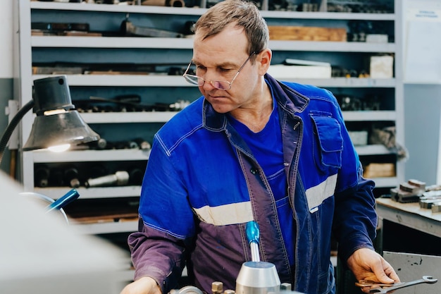 Torneiro adulto de 5055 anos trabalha em oficina atrás do torno Produção industrial de peças metálicas Trabalhador real