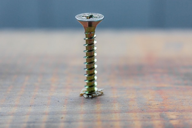 Foto el tornillo de metal se incrustó en la superficie de la tabla de madera con un concepto de reparación de casa o taller de destornillador