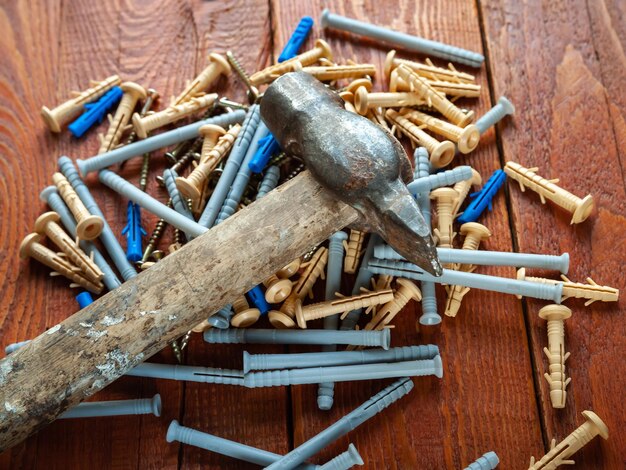 Tornillos de espiga de plástico y martillo sobre fondo de madera Enfoque selectivo