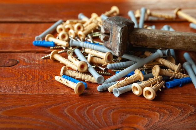 Tornillos de espiga de plástico y martillo sobre fondo de madera Enfoque selectivo