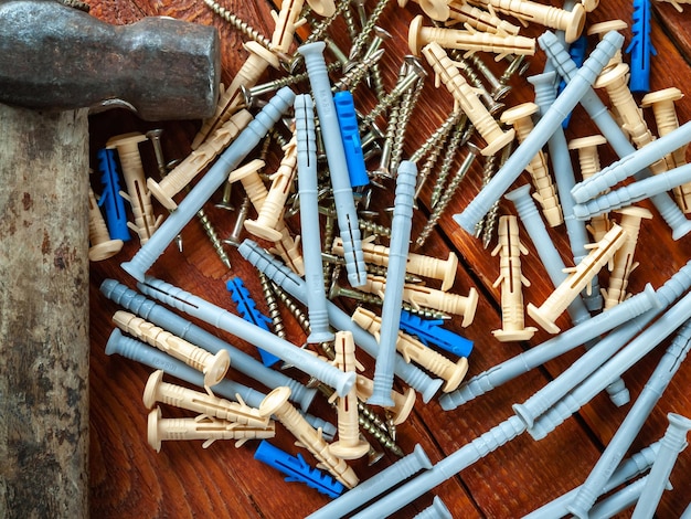 Tornillos de espiga de plástico y martillo sobre fondo de madera Enfoque selectivo