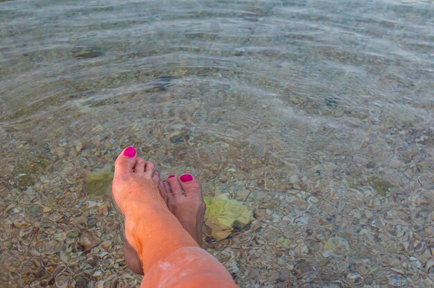 Tornozelos das pernas das mulheres em um mar quente e transparente Água limpa e pura