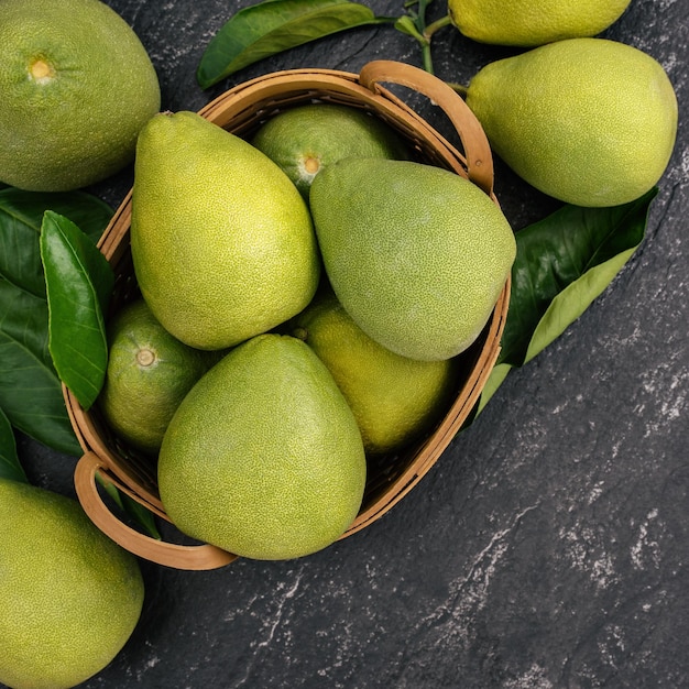 Toronja pomelo pomelo pelado fresco sobre fondo oscuro en una cesta de bambú Vista superior de la fruta de temporada de otoño vista plana de la mesa