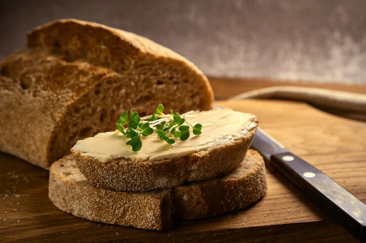 Torrada artesanal de pão com manteiga e brócolis microgreen em uma tábua de madeira com faca