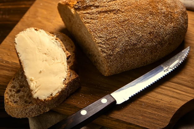 Torrada artesanal em fatias de pão com manteiga em uma tábua de madeira com faca