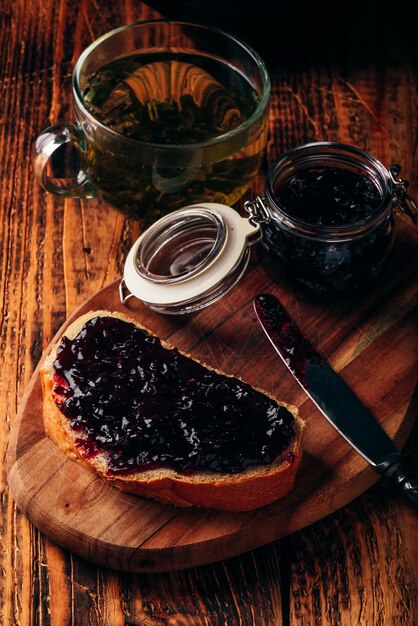 Torrada com geléia de frutas vermelhas na tábua e xícara de chá verde