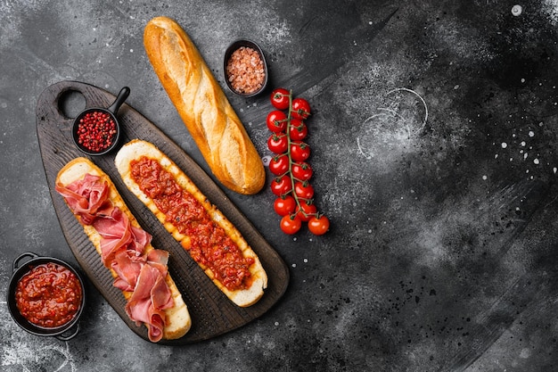 Torrada crocante com tomate fresco e presunto curado em fundo de mesa de pedra escura preta vista superior plana com espaço de cópia para texto