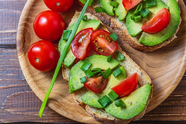 Torrada de abacate com tomate e cebola verde em uma fatia de pão de cenoura