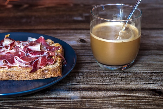 Torrada de café da manhã com tomate e presunto ibérico acompanhada de café com leite
