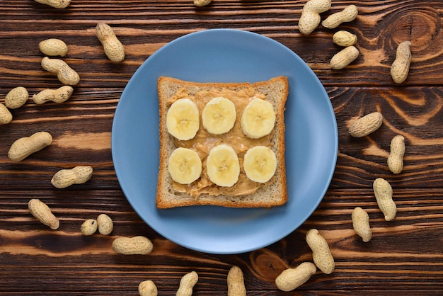 Torrada de manteiga de amendoim com fatias de banana em fundo de madeira