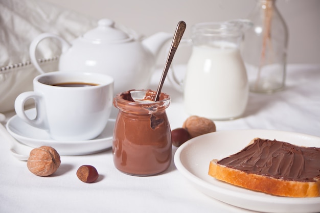 Foto torrada de pão com manteiga de creme de chocolate, xícara de café sobre fundo branco