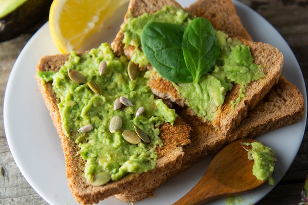 Torradas com guacamole, fatias de abacate. Comida saudável, lanche. Café da manhã. Mesa rústica de madeira.