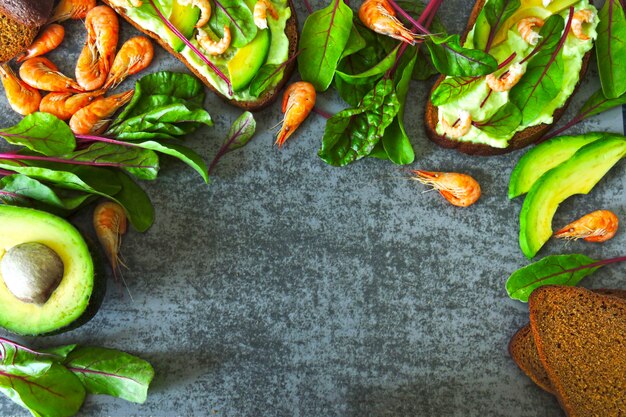 Torradas com pasta de abacate, camarão e acelga. Alimentação saudável. Sanduíches abertos vegetarianos úteis com abacate e camarão. Acelga para salada. Comida vegetariana. Superalimentos.