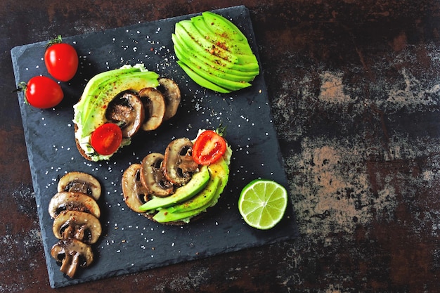 Torradas de abacate saudáveis com cogumelos e tomate cereja. Keto dieta.