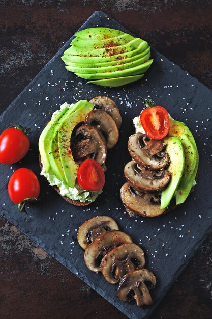 Torradas de abacate saudáveis com cogumelos e tomate cereja. Keto dieta.