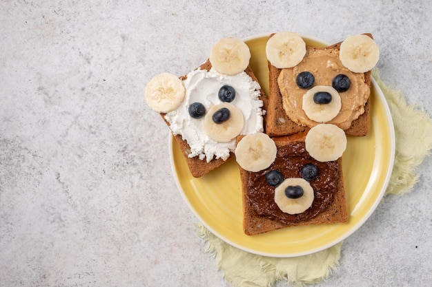 Torradas de café da manhã com manteiga de nozes e banana com cara de urso engraçado