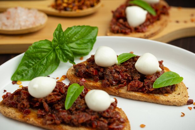 Foto torradas de caprese com queijo mozzarella tomates secos e manjericão comida tradicional da calábria antipasti