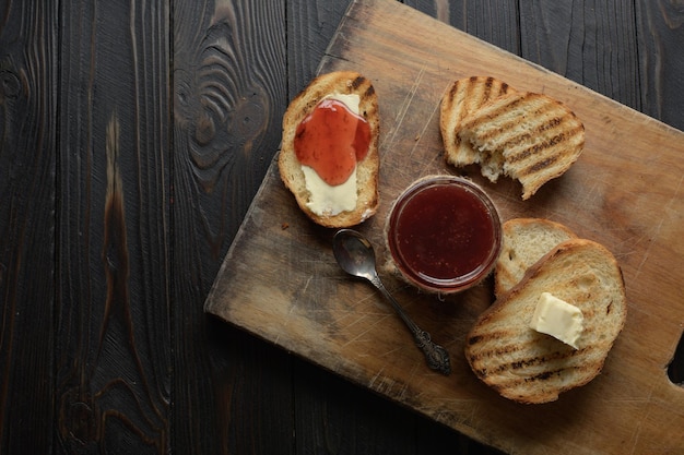 Torradas de pão com geleia de morango caseira e mesa rústica com manteiga no café da manhã ou brunch