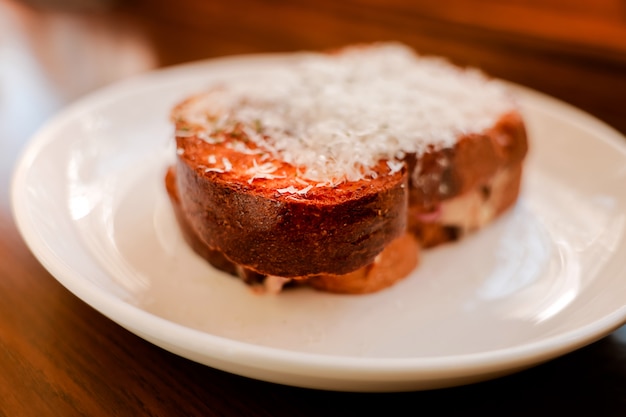 Foto torradas de pão com queijo na chapa branca. refeição da manhã no fim de semana acolhedor.