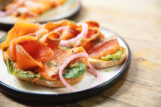 Torradas deliciosas com salmão defumado, abacate e folhas de manjericão