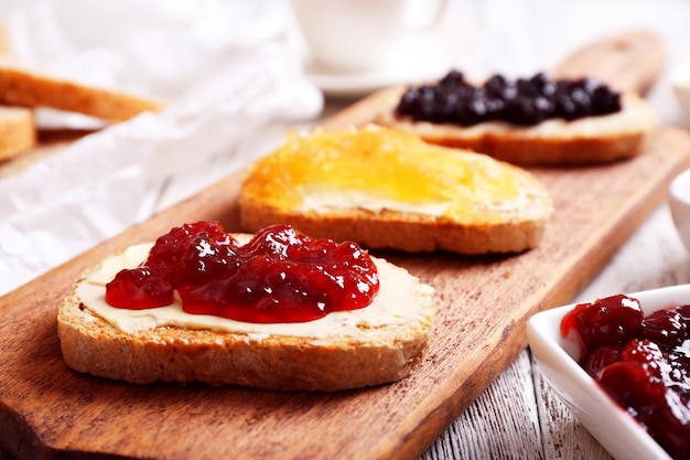 Torradas frescas com manteiga e geléias diferentes na mesa fecham