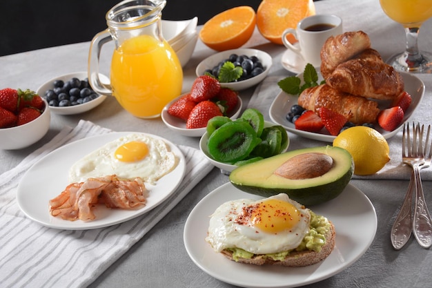 Torradas saudáveis de café da manhã com abacate e bacon de ovo e ovos frescos e suco fresco de frutas secas