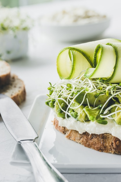 Torradas vegetarianas com vegetais verdes. Abacate, abobrinha, alfafa e ricota. Comida vegana.