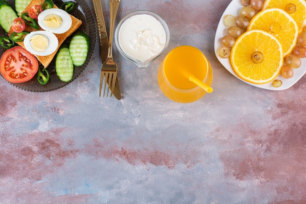 Torrar pão com ovos cozidos e prato de frutas na mesa de mármore.