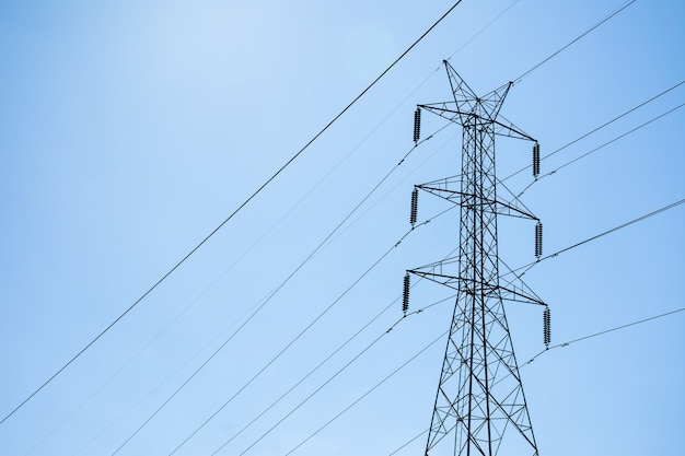 Torre de acero de energía eléctrica de alto voltaje contra el cielo azul y las nubes.