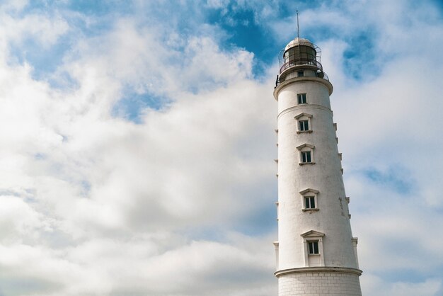 Torre alta do farol em um fundo de céu azul nublado