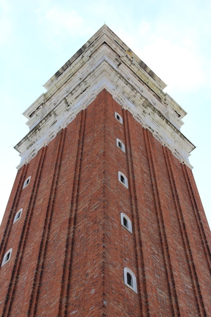 Una torre alta de ladrillo con una parte superior blanca