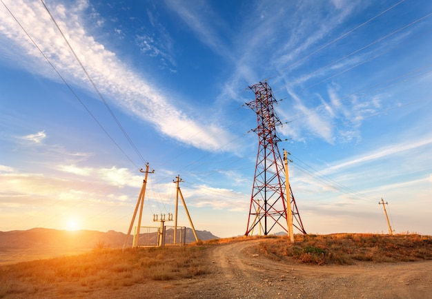 Torre de alta tensión en las montañas al atardecer. Sistema de pilón de electricidad