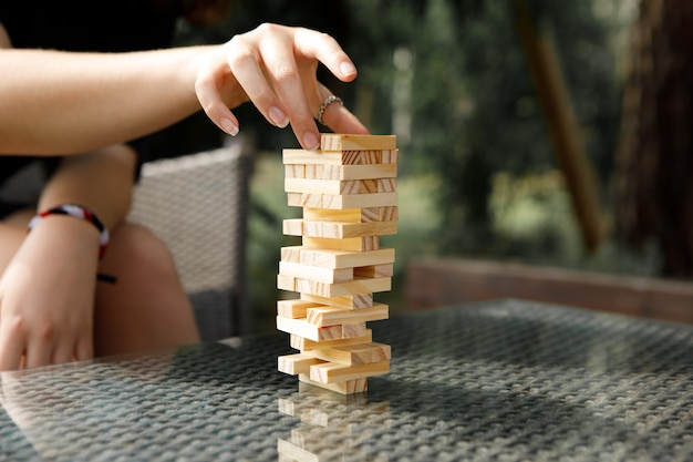 La torre de bloques de madera y la mano de la mujer toman un bloque.