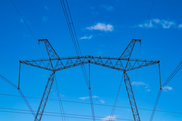 Torre con cables de transmisión de energía de alto voltaje contra el cielo azul