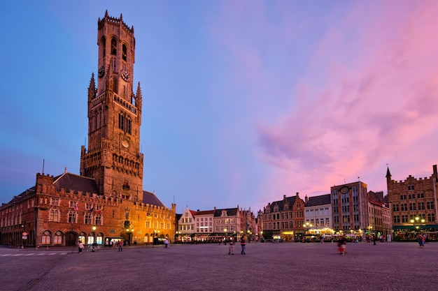 La torre del campanario y la plaza grote markt en brujas bélgica al atardecer en el crepúsculo