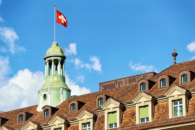 Foto torre com bandeira suíça e telhado coberto de telhas em berna, suíça