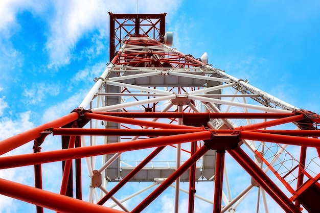 La torre de comunicación se alza contra el cielo con una vista de abajo hacia arriba