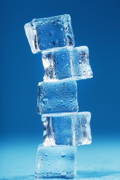 Torre de cubitos de hielo con gotas de agua en una fila sobre un fondo azul. Espacio libre